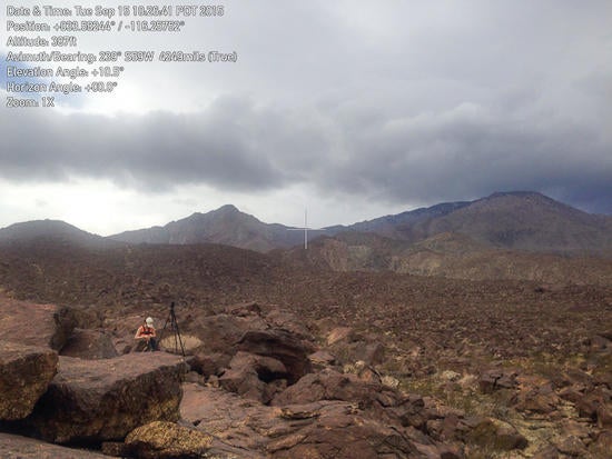 surveyor in a rocky bed with mountain background.  Measurements imposed over the image.